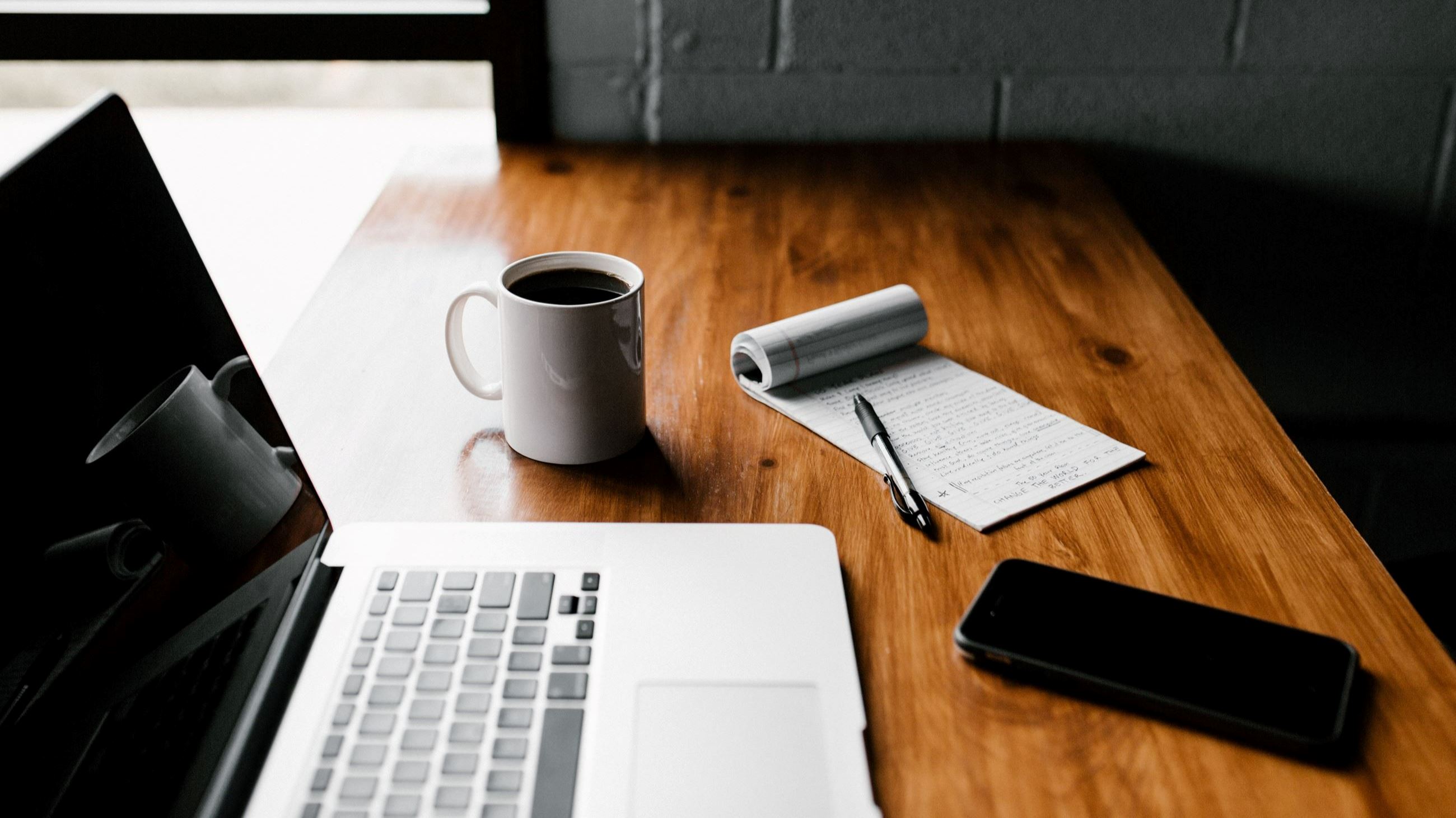 Computer on desk with cell phone and cup of coffee